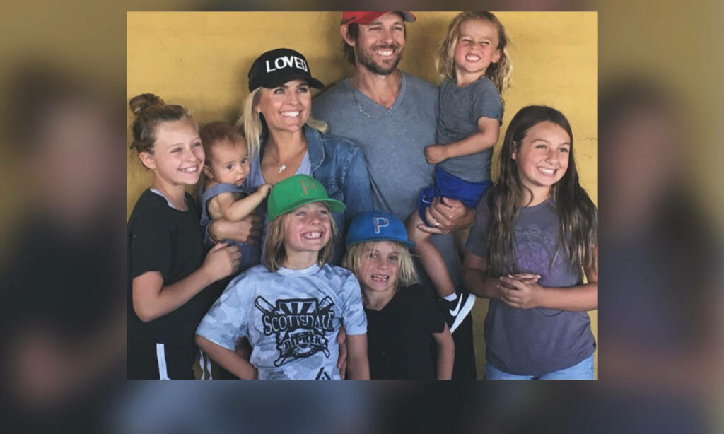 Aaron Baddeley and family smiling warmly against yellow wallpaper background joyful portrait