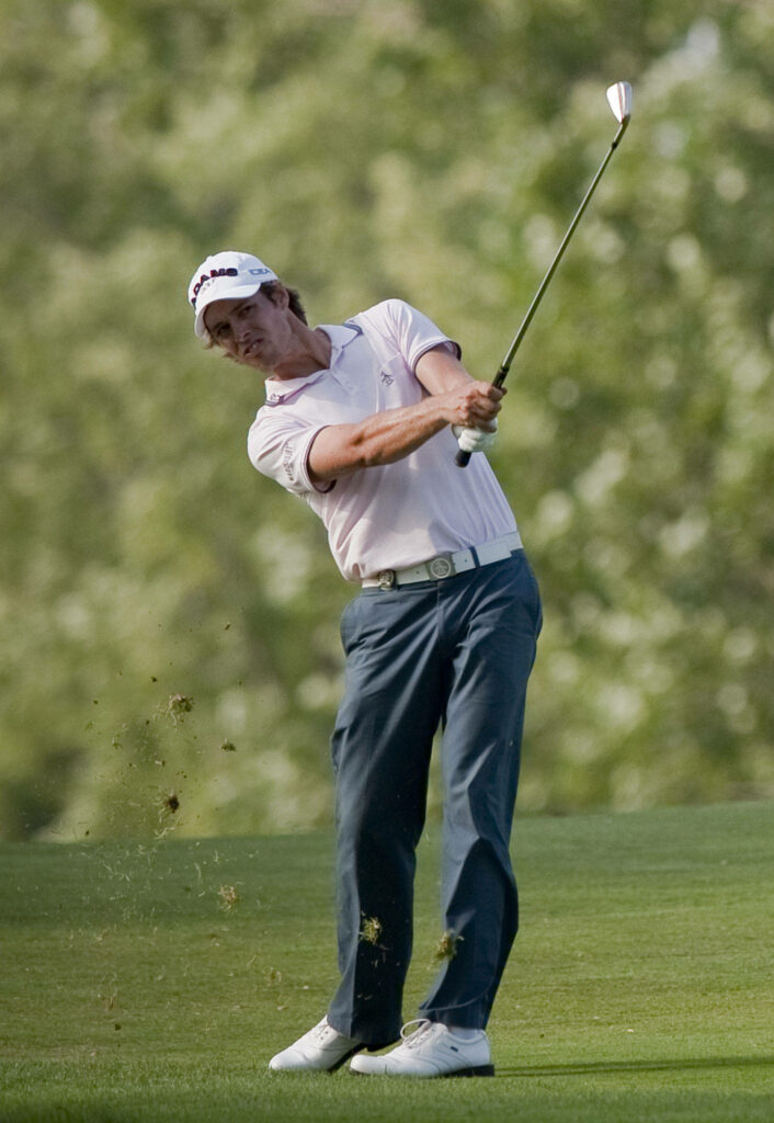 Aaron Baddeley swings golf club hitting grass in dynamic 2000 action shot wallpaper background