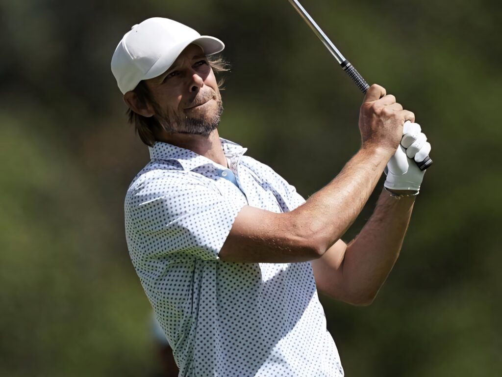 Aaron Baddeley mid-swing on golf course wearing white cap and polka dot shirt dynamic wallpaper
