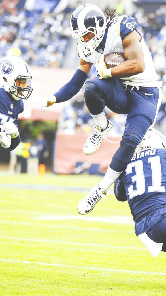 Aaron Donald overpowering Tennessee Titans defense in intense Los Angeles Rams football action Wallpaper