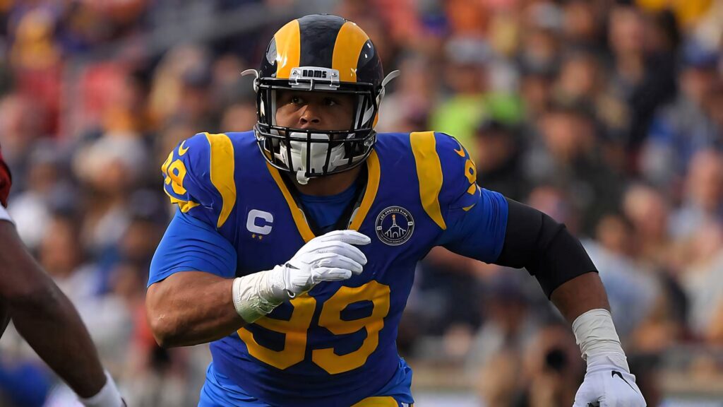 Aaron Donald in Los Angeles Rams uniform charging down the football field intense NFL action Wallpaper