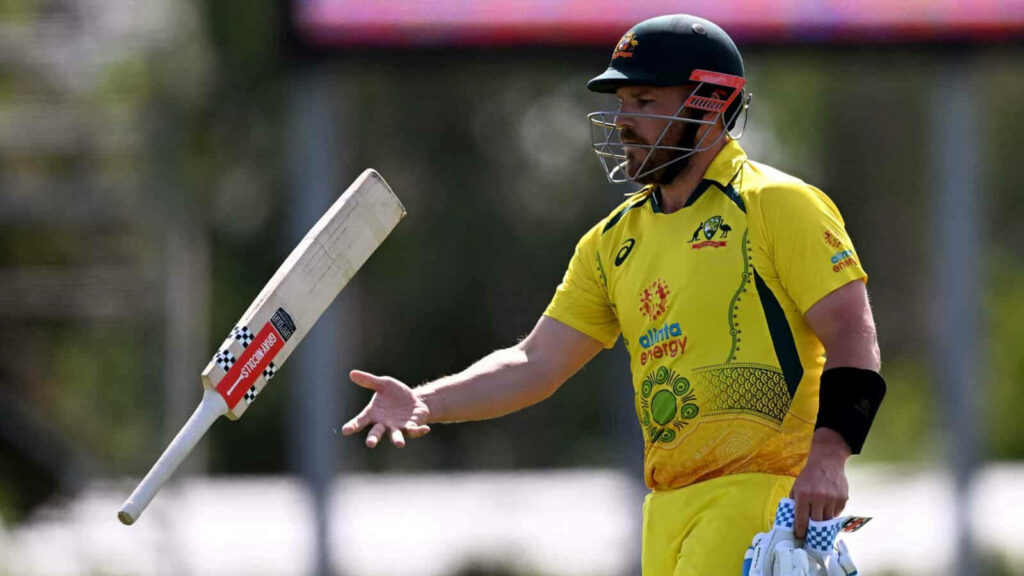 Aaron Finch in Australian yellow jersey confidently tossing bat during cricket match dynamic action Wallpaper