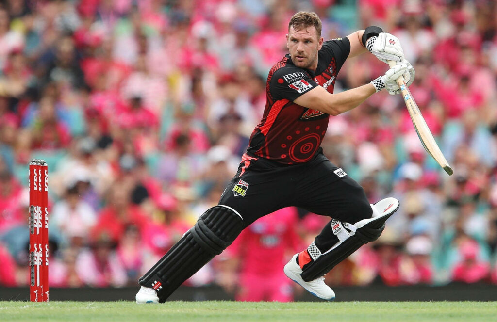 Aaron Finch batting dynamically in black and red cricket uniform on vibrant wallpaper background