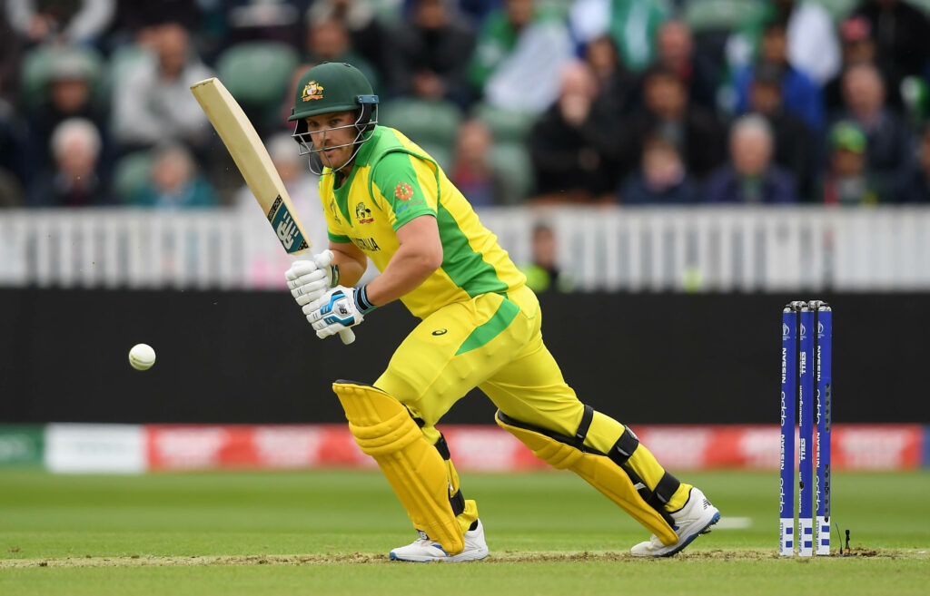 Aaron Finch in Australian jersey chasing cricket ball intensely during international match gameplay Wallpaper