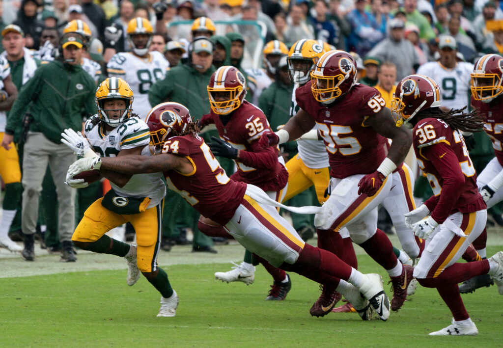 Aaron Jones Green Bay Packers sprinting past Washington defenders in intense NFL action wallpaper