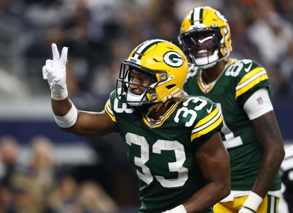 Aaron Jones Green Bay Packers number 33 jersey making victory sign during football game action Wallpaper