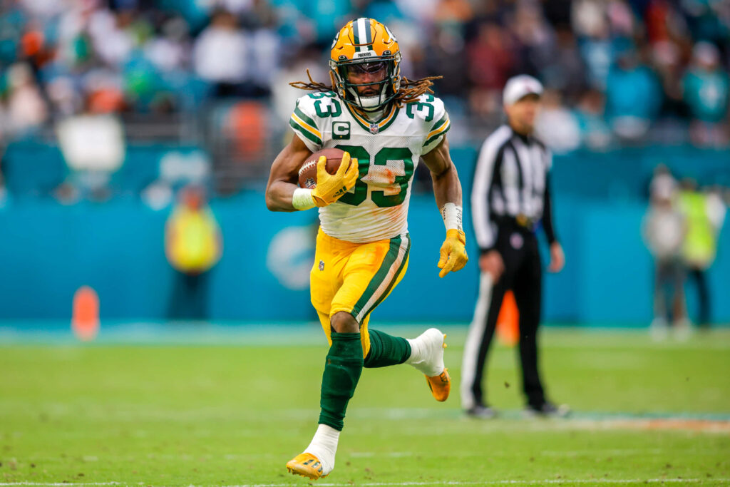 Aaron Jones Green Bay Packers running back charging down field in intense NFL game action wallpaper