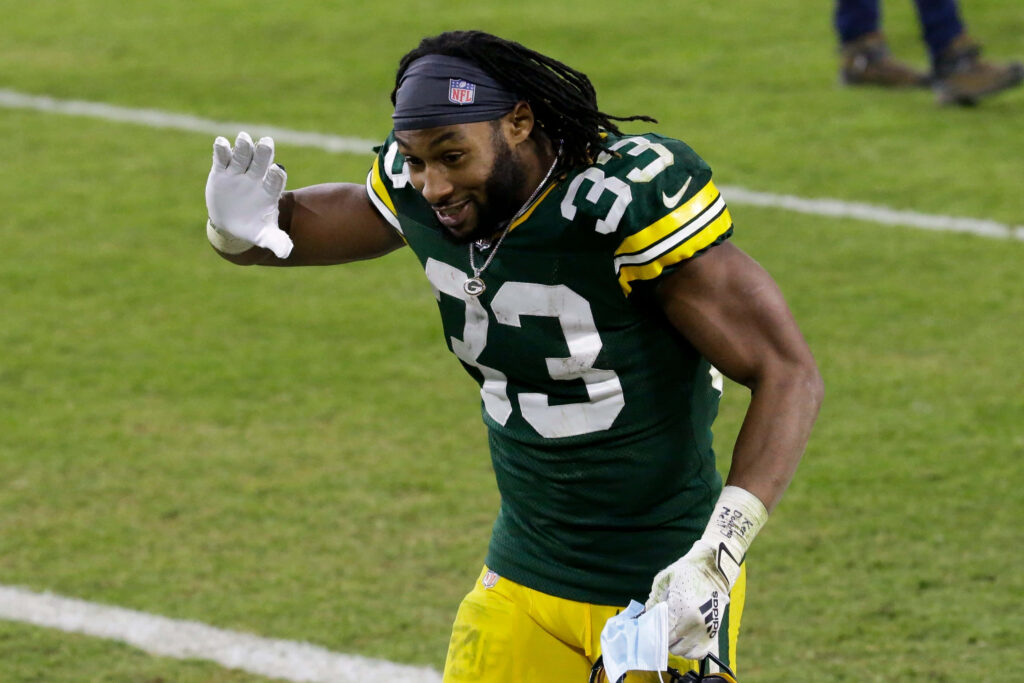Green Bay Packers Aaron Jones #33 smiling and waving on field showing team spirit and athleticism Wallpaper