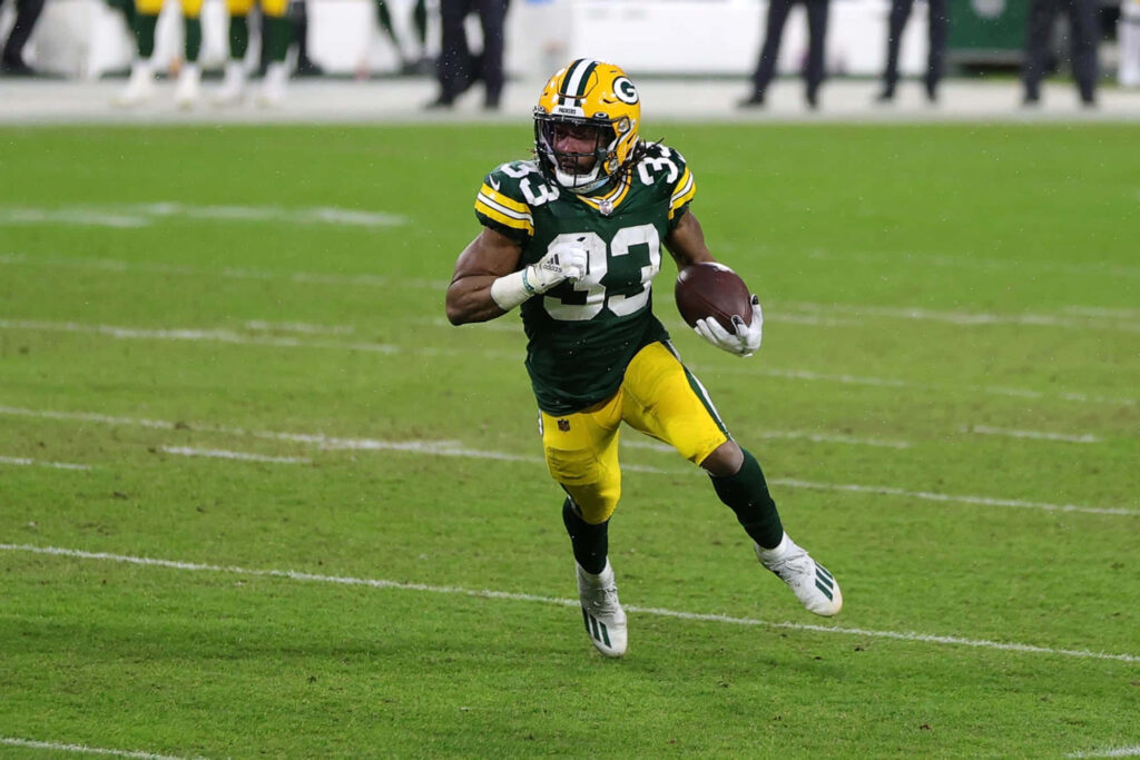Aaron Jones Green Bay Packers sprinting with football showcasing athleticism and determination Wallpaper