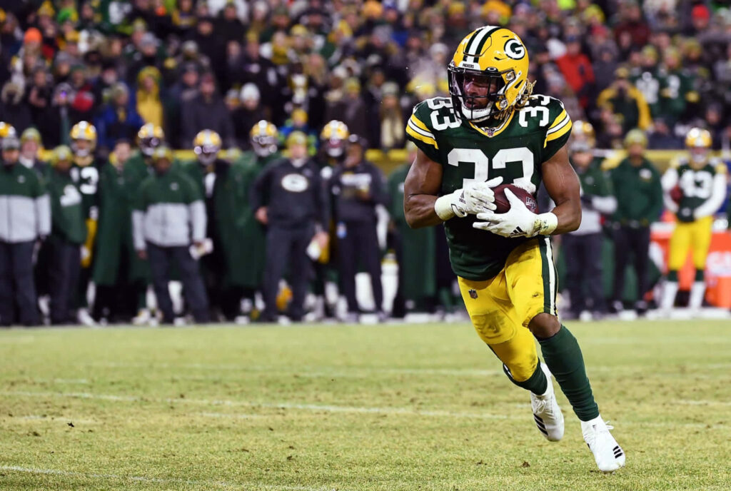 Aaron Jones Green Bay Packers sprinting during intense football game showcasing athleticism and skill Wallpaper