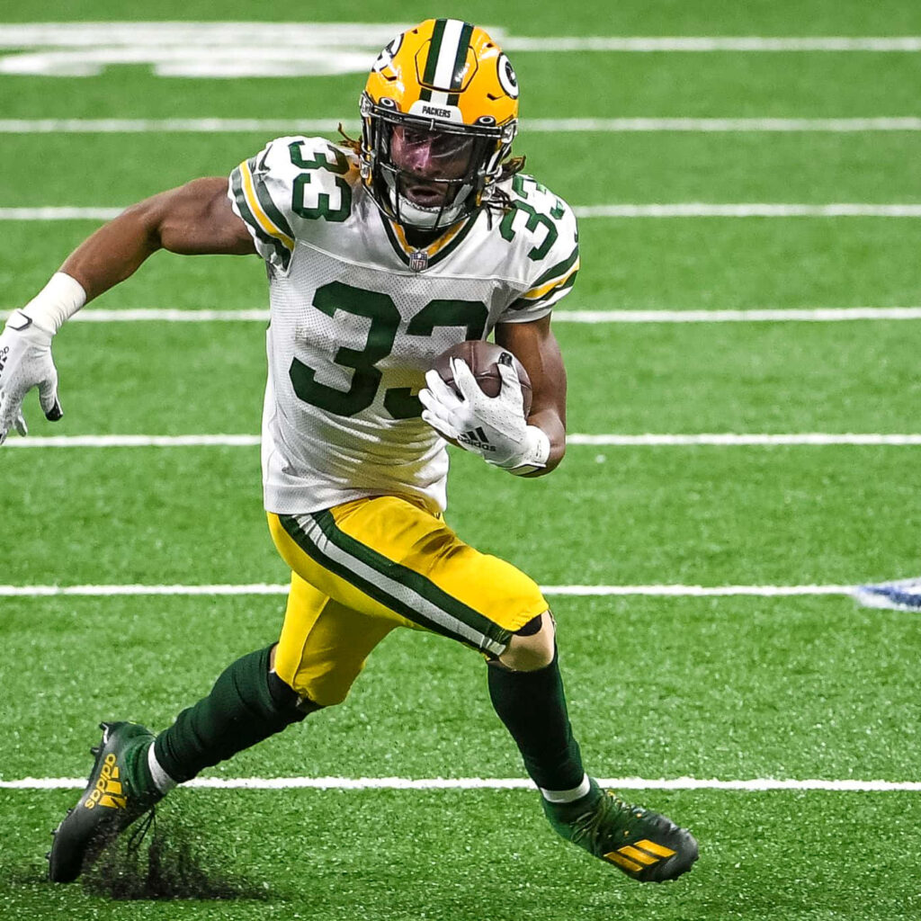 Aaron Jones celebrates touchdown sprint in Green Bay Packers uniform during intense football game Wallpaper