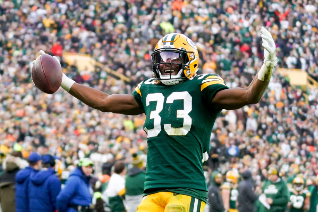 Aaron Jones Green Bay Packers touchdown celebration with energetic Lambeau Field crowd background Wallpaper