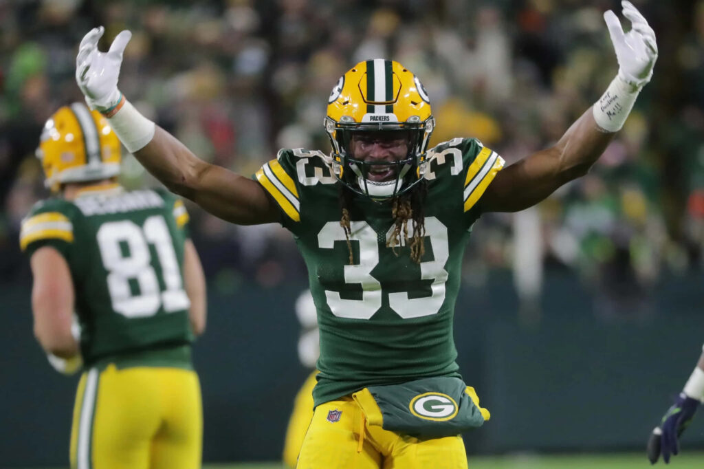 Green Bay Packers running back Aaron Jones celebrates touchdown with arms raised on field wallpaper