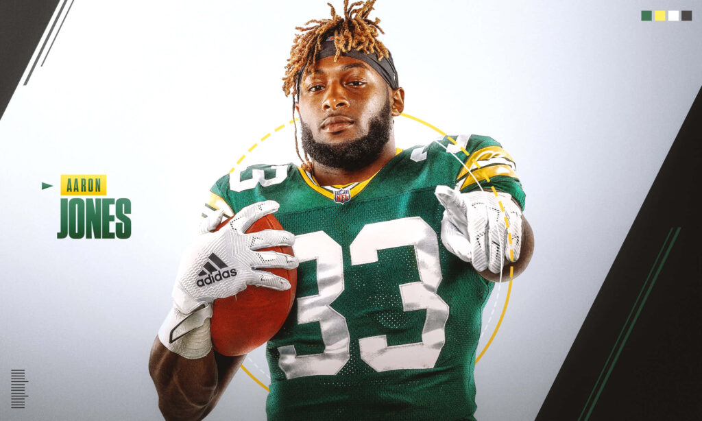 Aaron Jones Green Bay Packers in uniform holding football pointing with intensity dynamic wallpaper