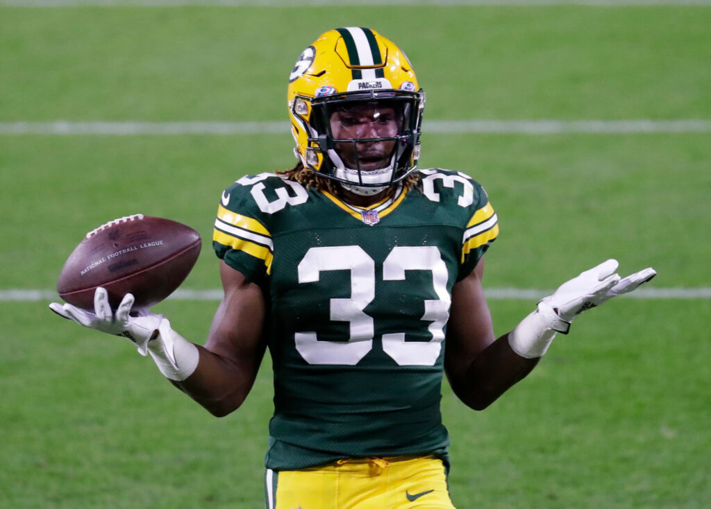 Aaron Jones Green Bay Packers football player in green and yellow uniform holding ball on field Wallpaper