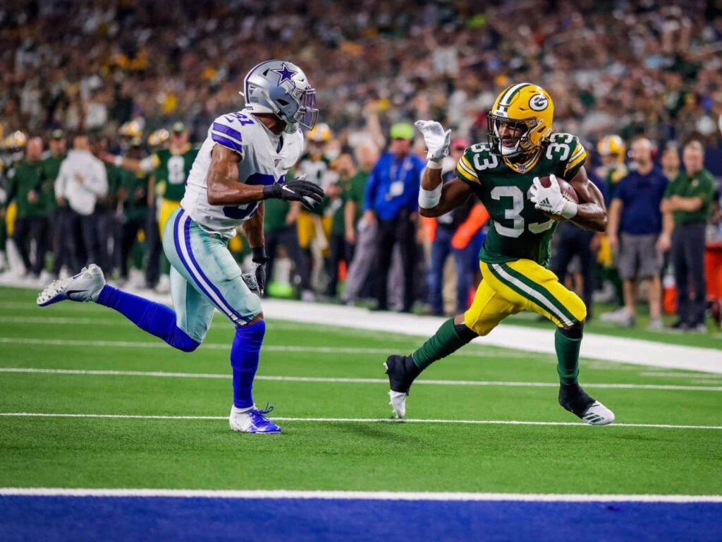 Aaron Jones sprinting past defender showcasing agility and speed in dynamic NFL game action wallpaper
