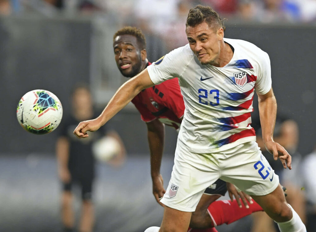 Aaron Long in 2019 USA soccer jersey showing focus and determination on the field game action Wallpaper
