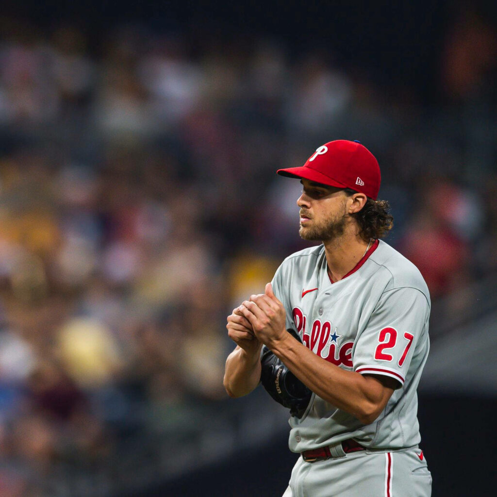 Aaron Nola in Philadelphia Phillies uniform focused on field with blurred crowd background wallpaper