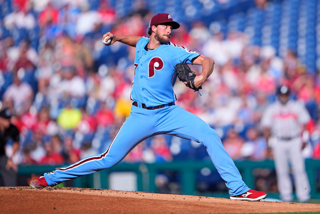 Aaron Nola pitching in Phillies uniform during intense game with stadium crowd background wallpaper