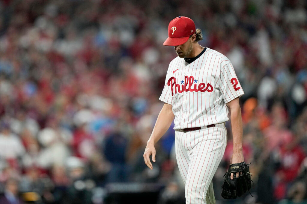 Aaron Nola in Phillies uniform walking off mound with head down against blurred stadium crowd Wallpaper