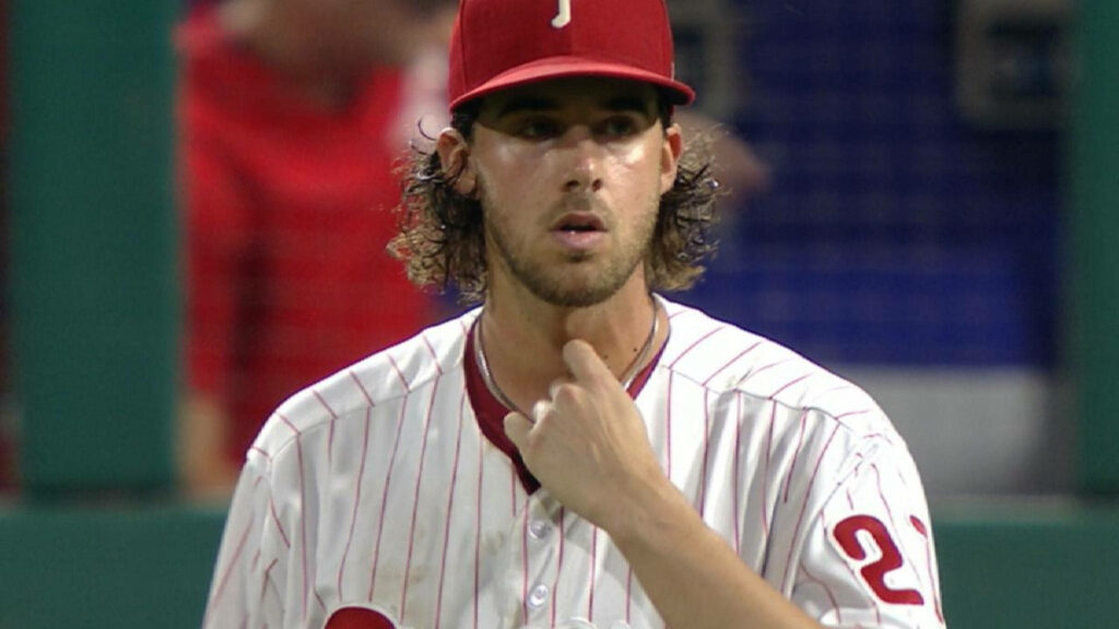 Aaron Nola in Phillies uniform scratching throat during game on wallpaper background