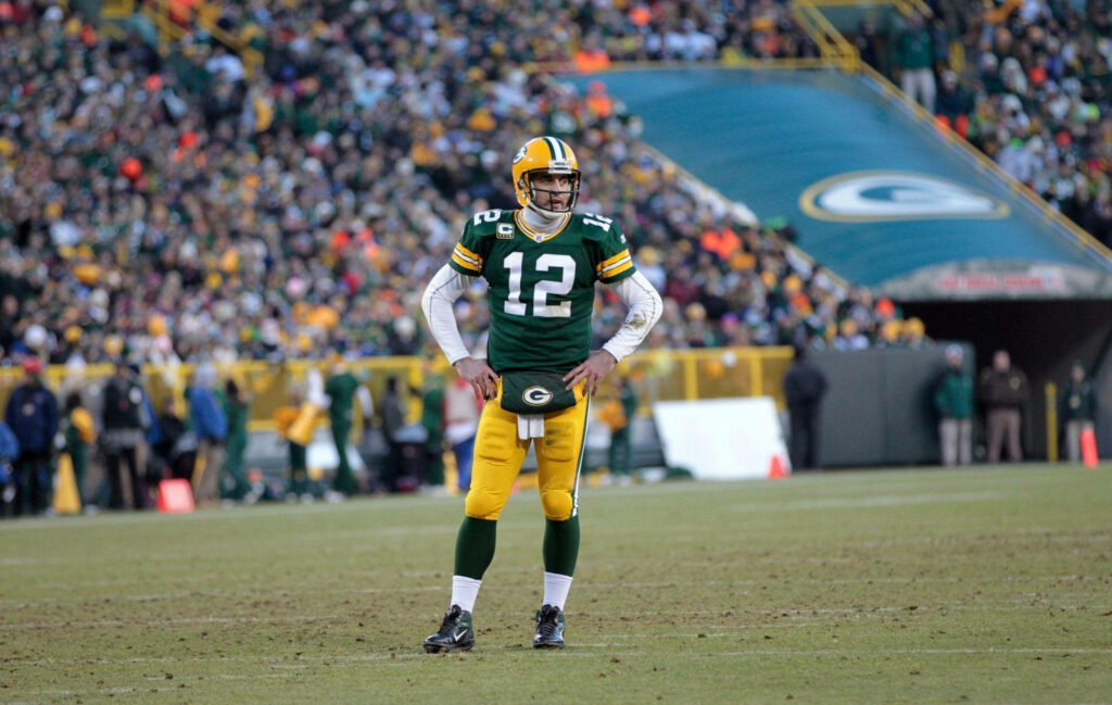 Aaron Rodgers in Green Bay Packers uniform on field with packed stadium and cheering fans Wallpaper