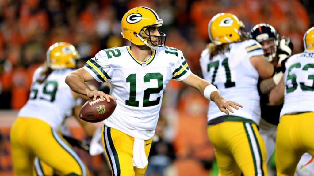 Aaron Rodgers in number 12 Packers jersey throwing a pass during intense NFL game action Wallpaper
