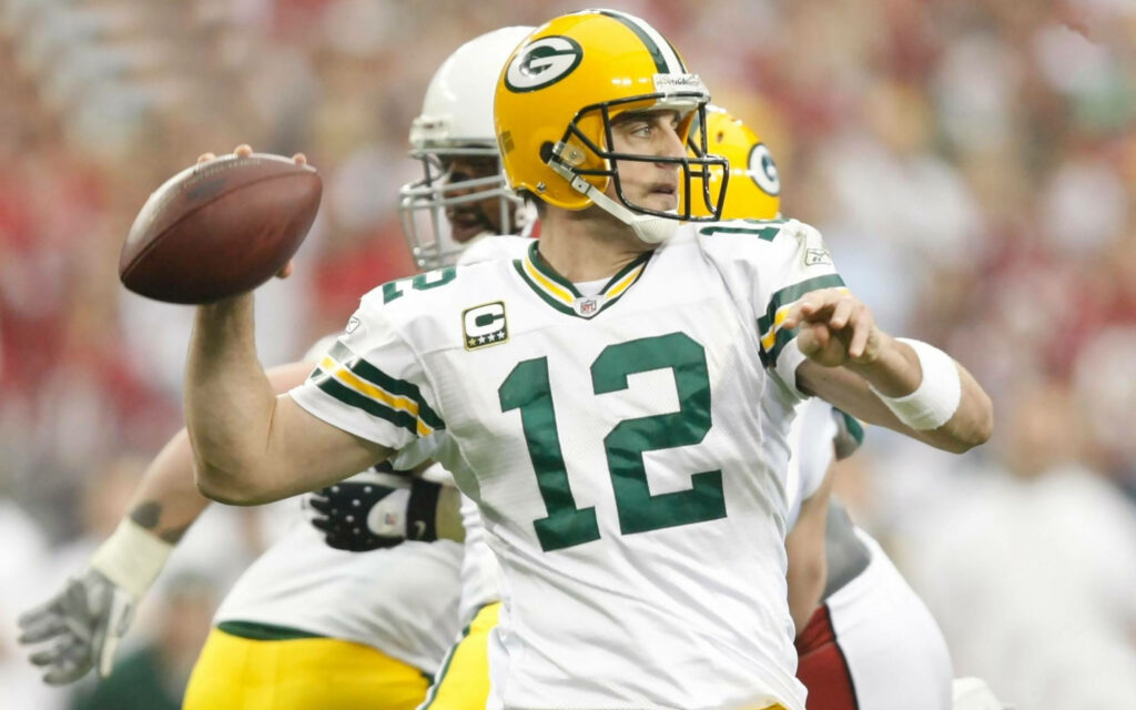 Aaron Rodgers focused throwing football in intense Green Bay Packers NFL game wallpaper background