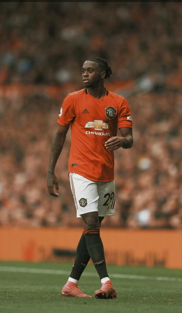 Aaron Wan-Bissaka Manchester United kit on pitch vibrant orange background football fan wallpaper