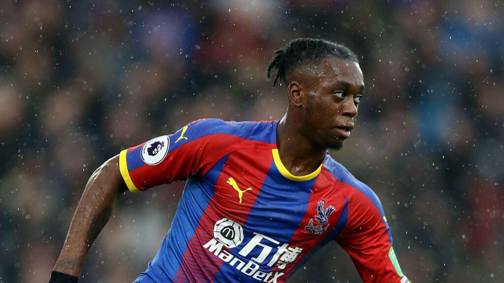 Aaron Wan-Bissaka in Crystal Palace kit sprinting intensely during a heated football match Wallpaper