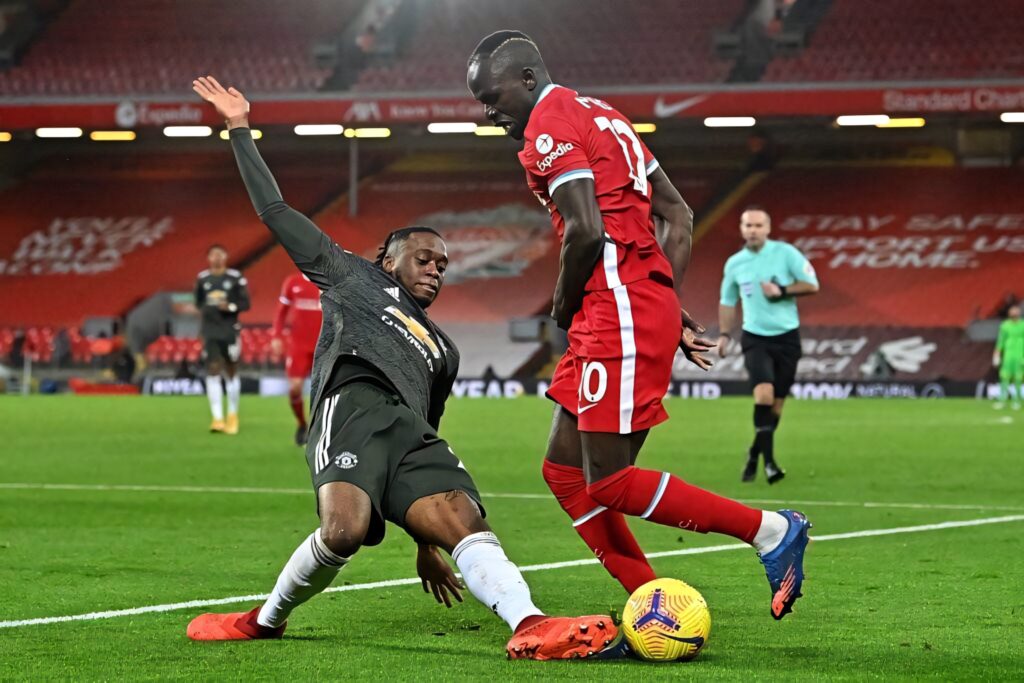 Aaron Wan-Bissaka falling while defending aggressively in an intense football match wallpaper background