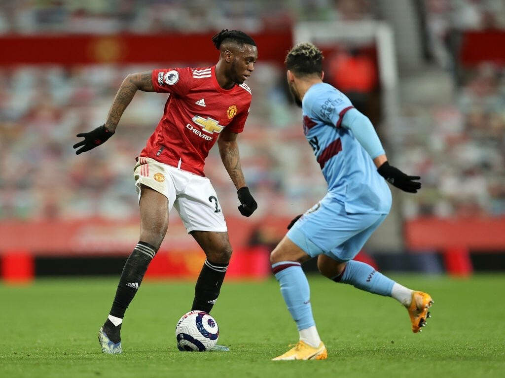 Aaron Wan-Bissaka defending aggressively in football match showcasing top defensive skills on pitch Wallpaper