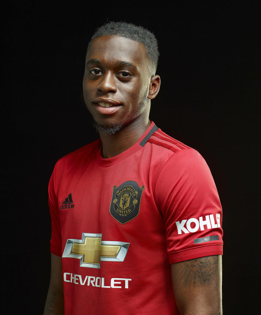 Aaron Wan-Bissaka in Manchester United home kit confident pose dark background wallpaper