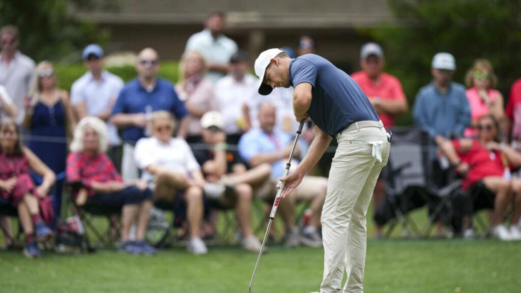 Aaron Wise focused lining up a putt on the green with a crowd watching golf tournament wallpaper