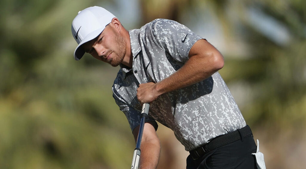 Aaron Wise focusing on golf shot in patterned polo and white cap outdoors blurred background Wallpaper