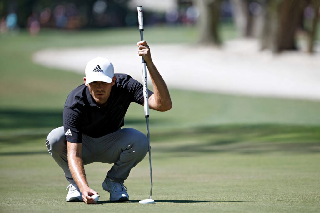 Aaron Wise focused lining up a putt on the golf course in dynamic wallpaper background