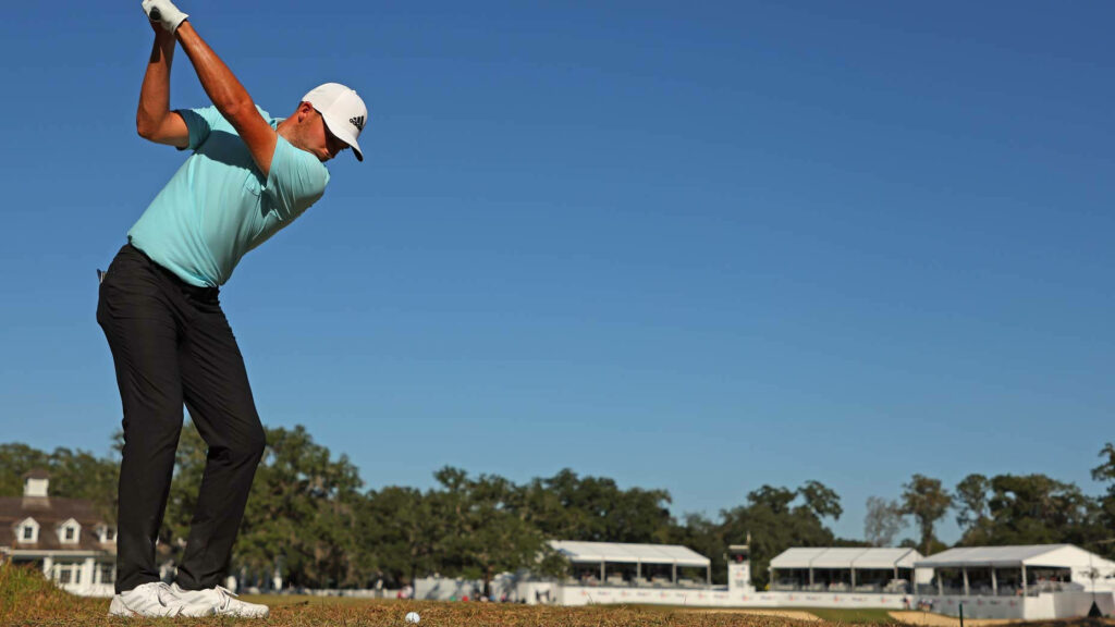 Golfer Aaron Wise preparing powerful swing on sunny golf course with blue skies and tents Wallpaper