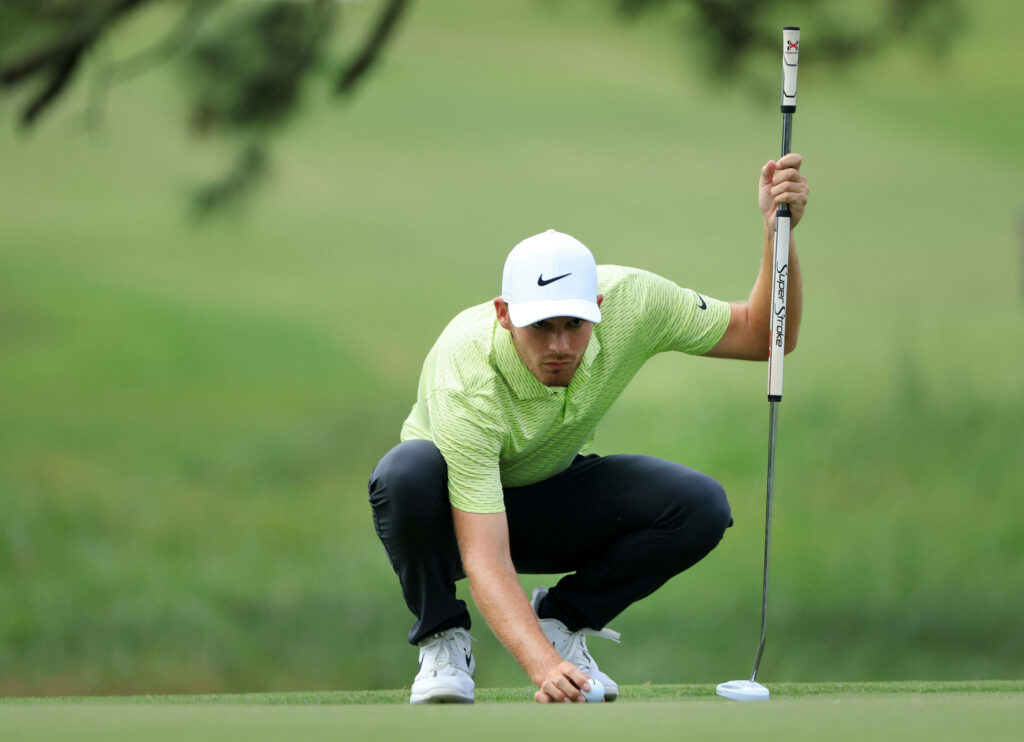 Aaron Wise focused on measuring golf shot on green showcasing precision in striking golf wallpaper