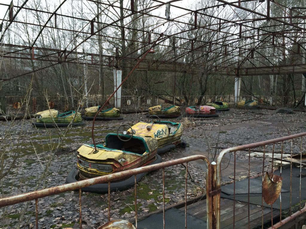 Abandoned Chernobyl amusement park rusted bumper cars overgrown plants gray sky wallpaper