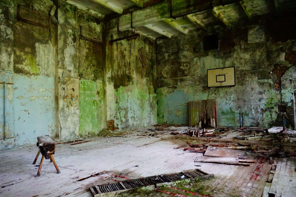 Abandoned Chernobyl basketball court with rusted hoop faded walls and decaying wooden floor Wallpaper