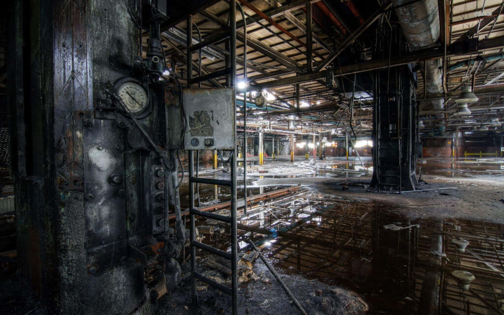 Abandoned factory wallpaper with rusted machinery exposed pipes and metal beams in water pools