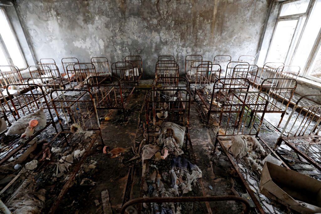 Abandoned room with rusty bed frames and peeling walls evoking haunting post-apocalyptic decay Wallpaper