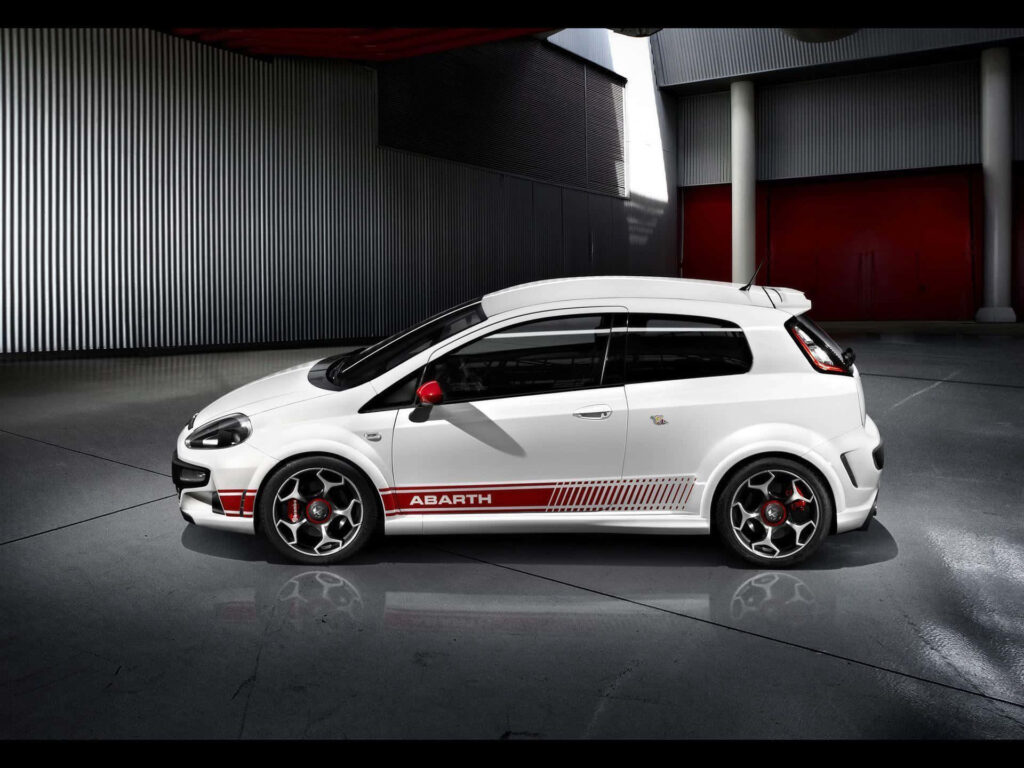Abarth racing car in industrial setting with white sporty finish and red accents wallpaper background