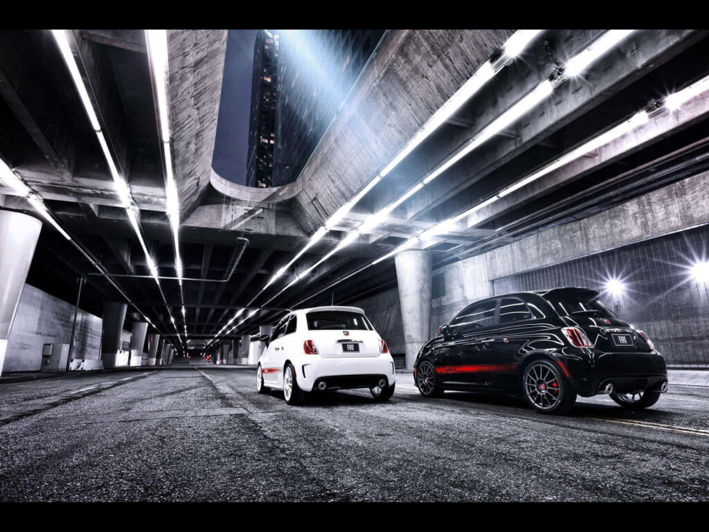 Two Abarth sportscars under urban overpass with dramatic lighting sleek design wallpaper background