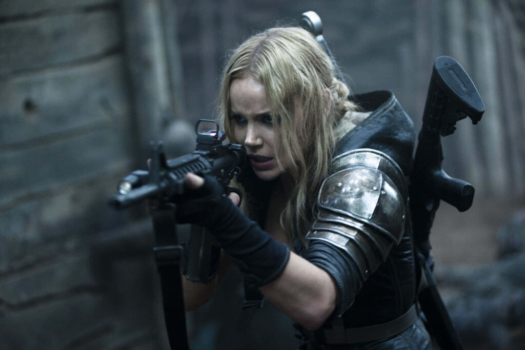 Abbie Cornish in tactical gear aiming rifle in intense action movie scene wallpaper background