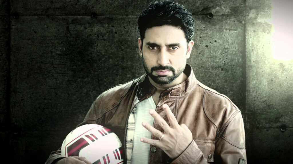 Abhishek Bachchan in brown leather jacket holding football against rugged concrete wall background Wallpaper