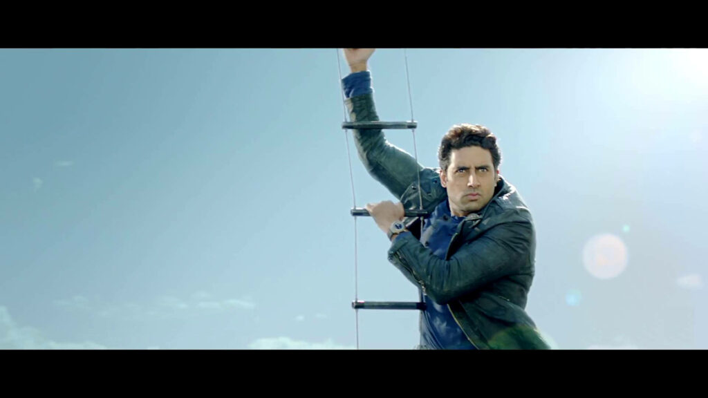 Abhishek Bachchan hanging on rope ladder against clear blue sky dramatic fun wallpaper background