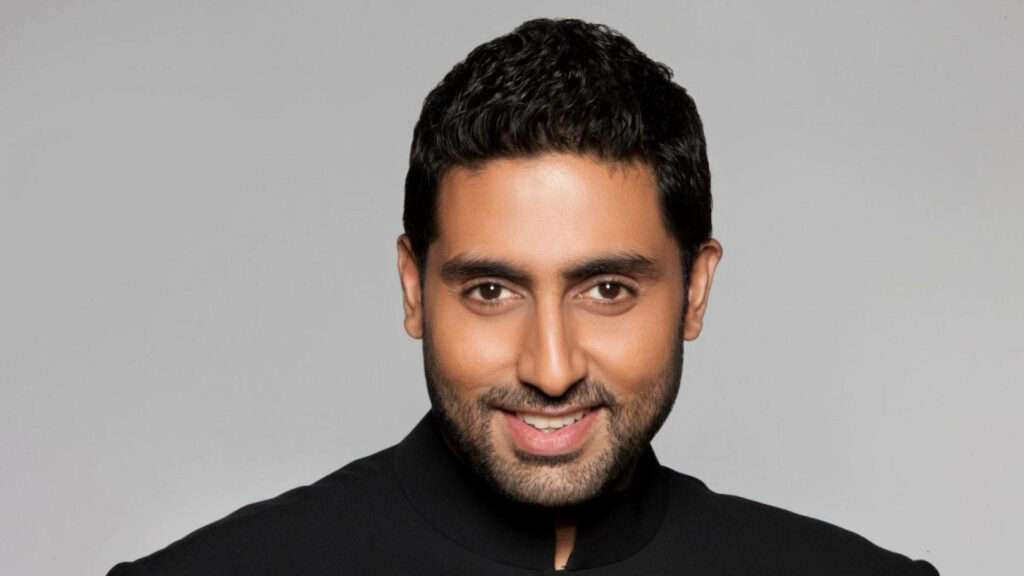 Close up of Abhishek Bachchan smiling against a light background charismatic wallpaper image