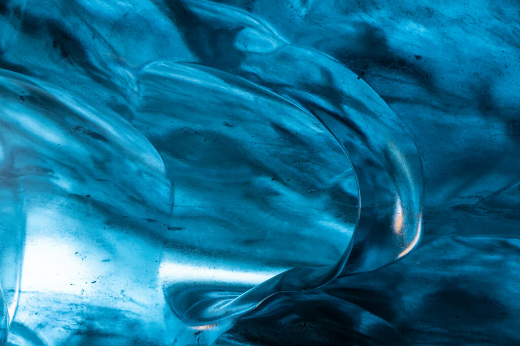 Abstract close-up of natural blue ice formations with swirling patterns and smooth curves wallpaper