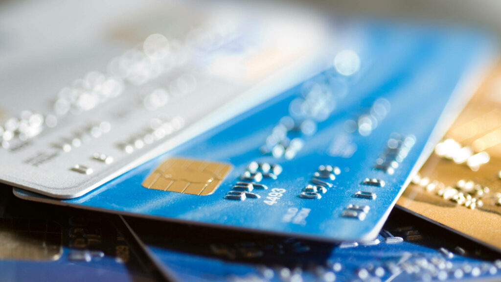 Blurred close-up of overlapping blue silver credit cards with shiny chips and embossed numbers Wallpaper